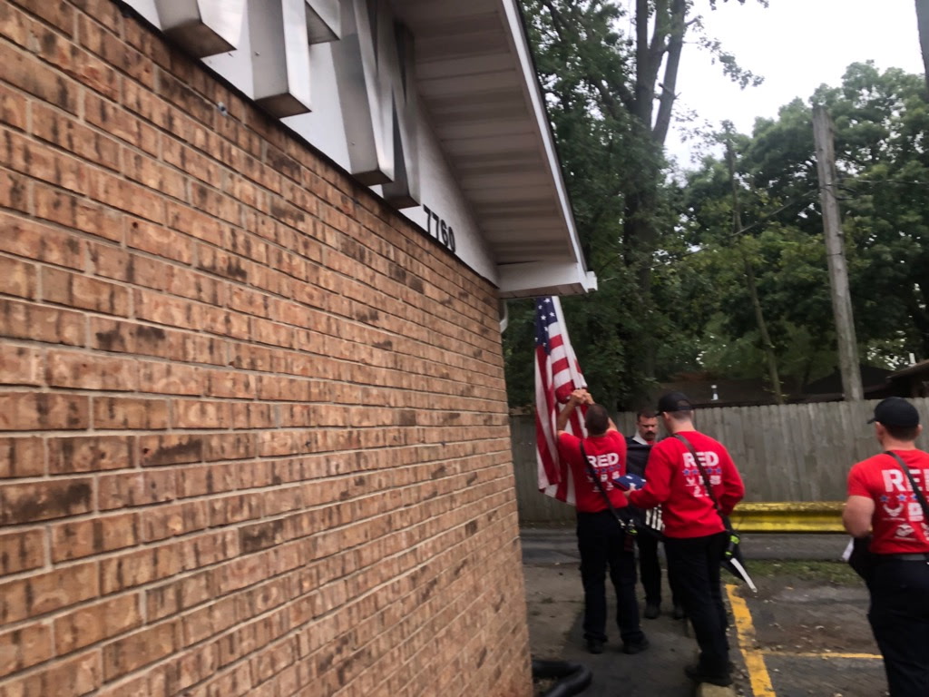 Portage Fire Department members in RED shirts handling the American flag outside VFW Post 7760