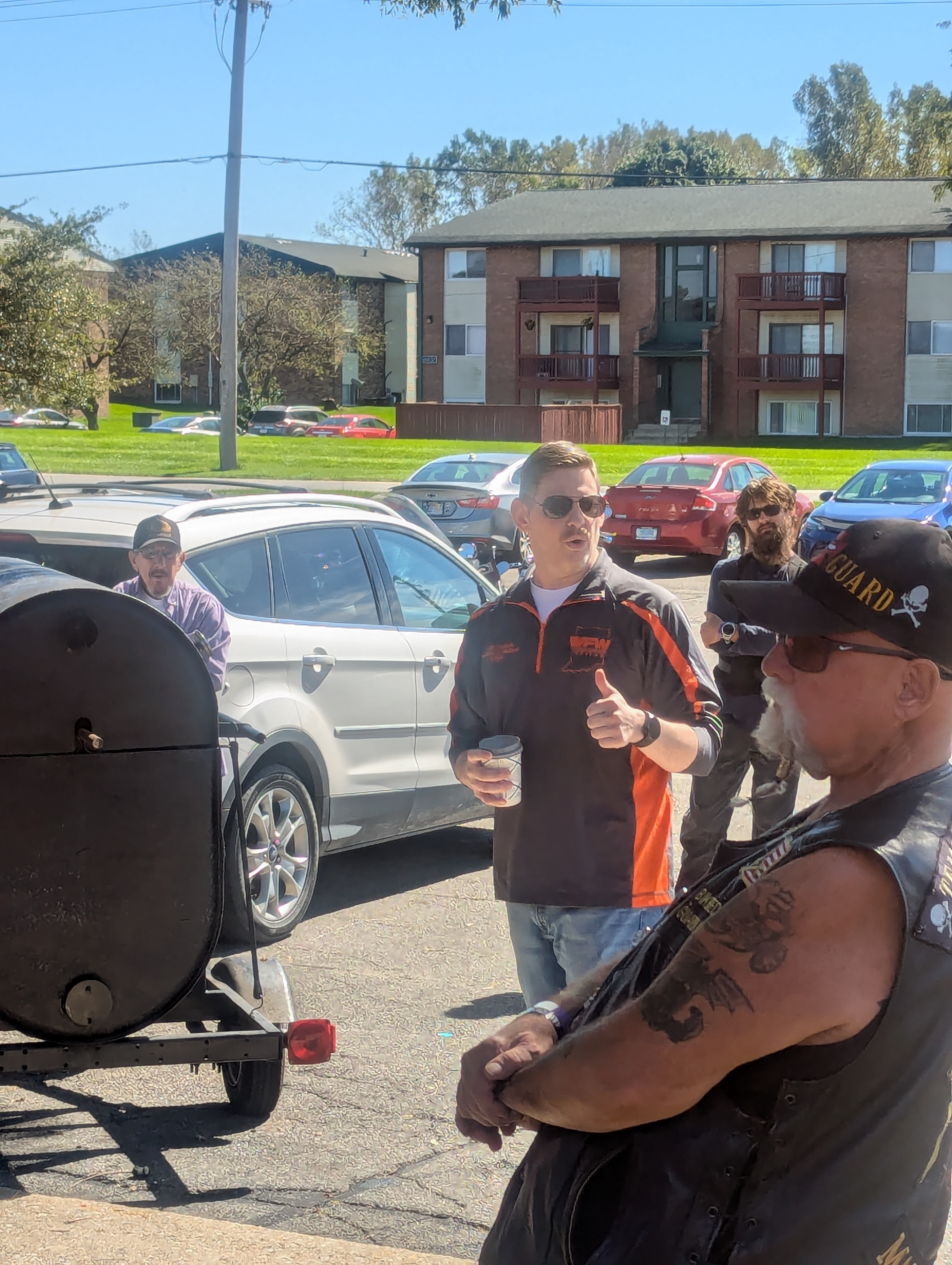 VFW Post 7760 member with thumbs up next to the BBQ smoker at Hogs For Hope